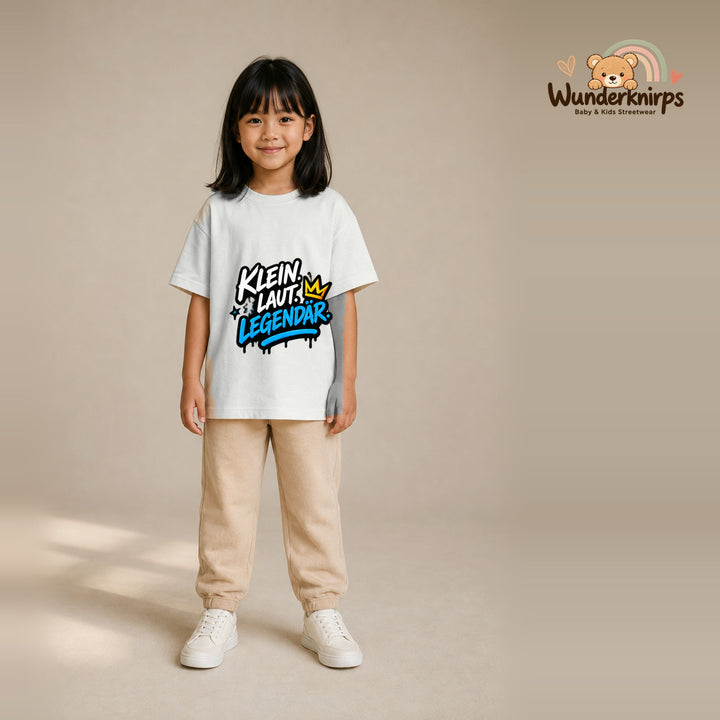 T-Shirt für Mädchen in Weiß mit Motiv „Klein laut legendär“, getragen von einem Kind – Wunderknirps.