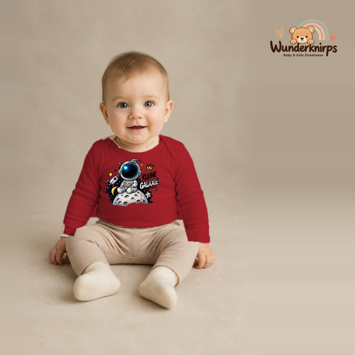Babybody für Jungen in Rot mit Motiv „Kleine Galaxie“, getragen von einem Kind – Wunderknirps.