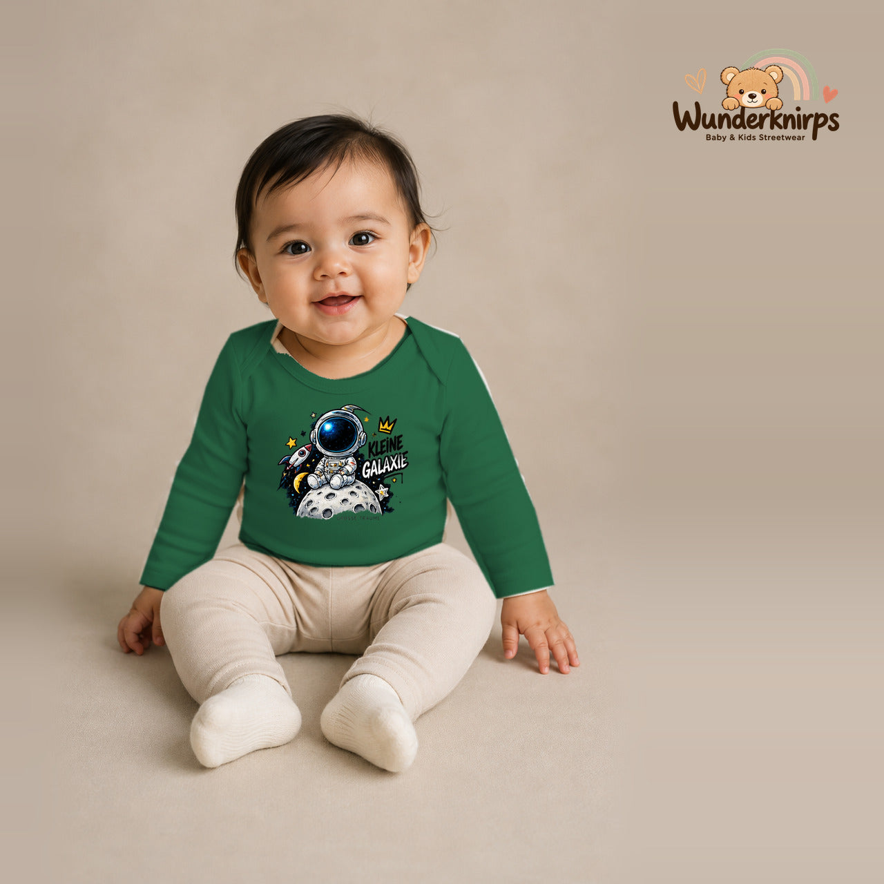 Babybody für Mädchen in Grün mit Motiv „Kleine Galaxie“, getragen von einem Kind – Wunderknirps.