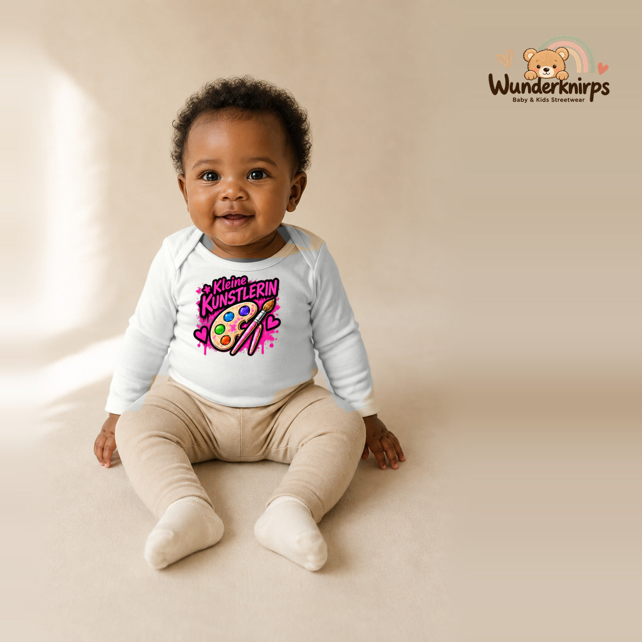 Babybody für Mädchen in Weiß mit Motiv „Kleine Künstlerin“, getragen von einem Kind – Wunderknirps.