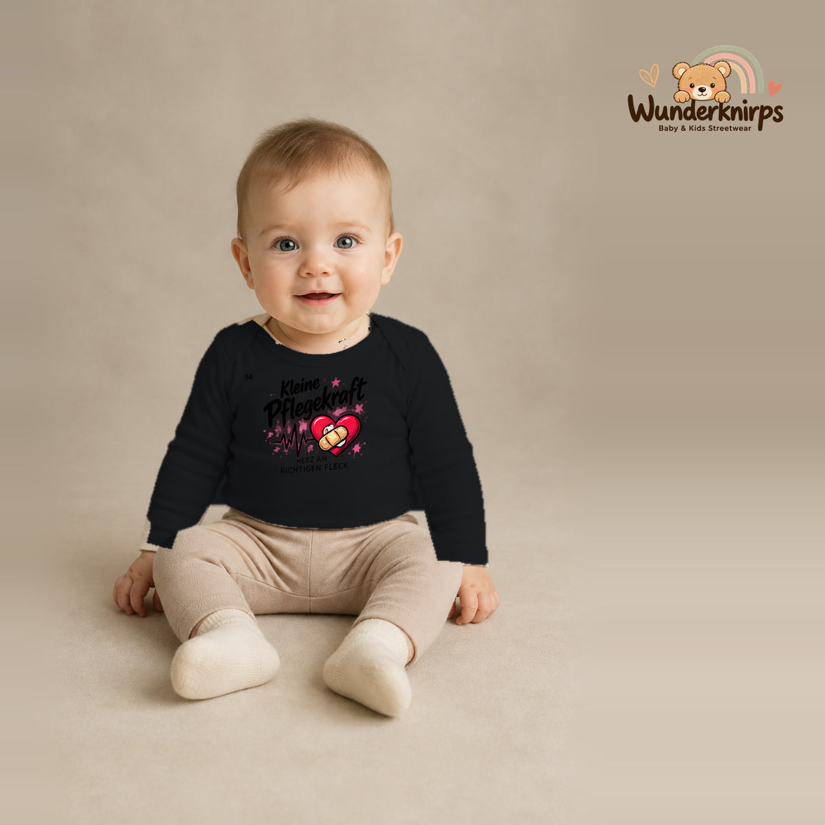 Babybody für Jungen in Schwarz mit Motiv „Kleine Pflegekraft“, getragen von einem Kind – Wunderknirps.