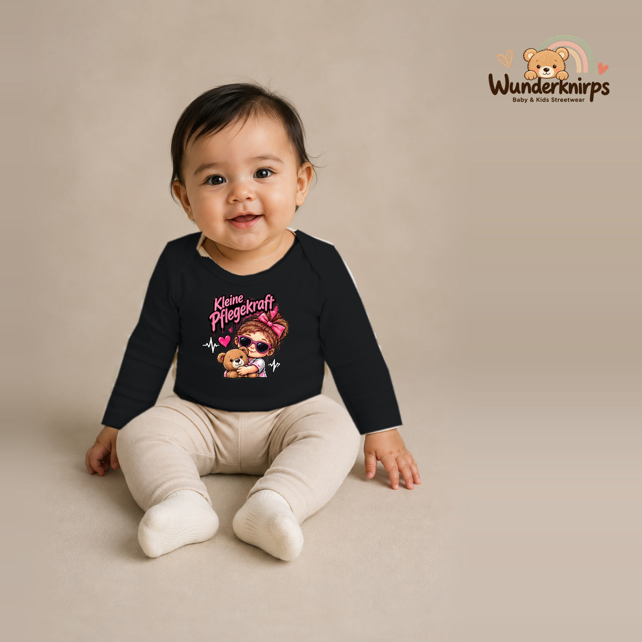 Babybody für Mädchen in Schwarz mit Motiv „Kleine Pflegekraft“, getragen von einem Kind – Wunderknirps.