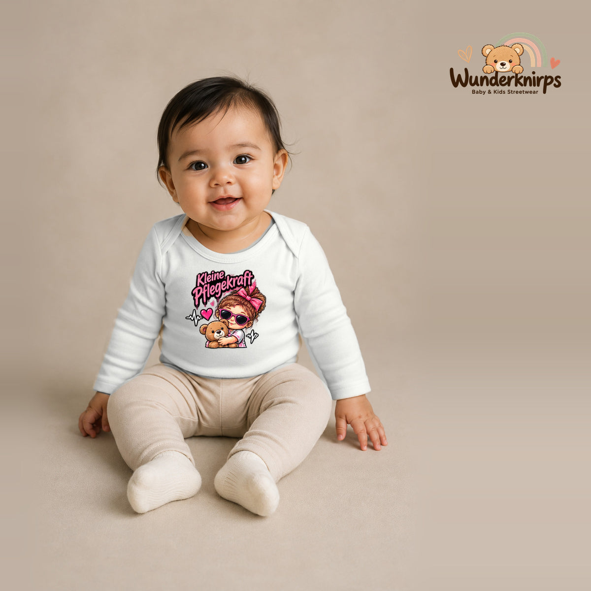 Babybody für Mädchen in Weiß mit Motiv „Kleine Pflegekraft“, getragen von einem Kind – Wunderknirps.