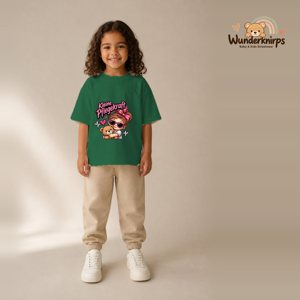 T-Shirt für Mädchen in Grün mit Motiv „Kleine Pflegekraft“, getragen von einem Kind – Wunderknirps.
