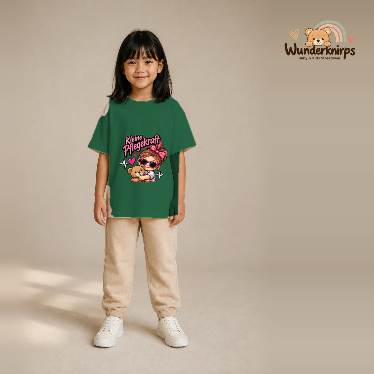 T-Shirt für Mädchen in Grün mit Motiv „Kleine Pflegekraft“, getragen von einem Kind – Wunderknirps.