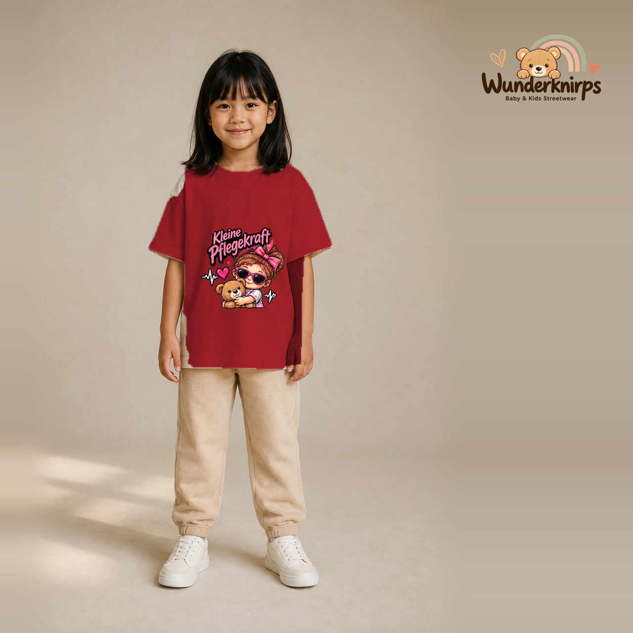 T-Shirt für Mädchen in Rot mit Motiv „Kleine Pflegekraft“, getragen von einem Kind – Wunderknirps.
