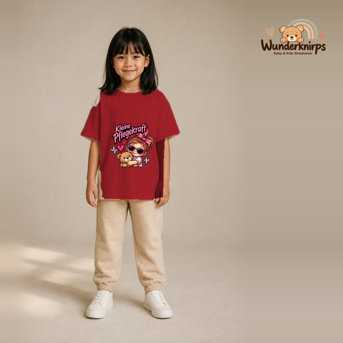 T-Shirt für Mädchen in Rot mit Motiv „Kleine Pflegekraft“, getragen von einem Kind – Wunderknirps.