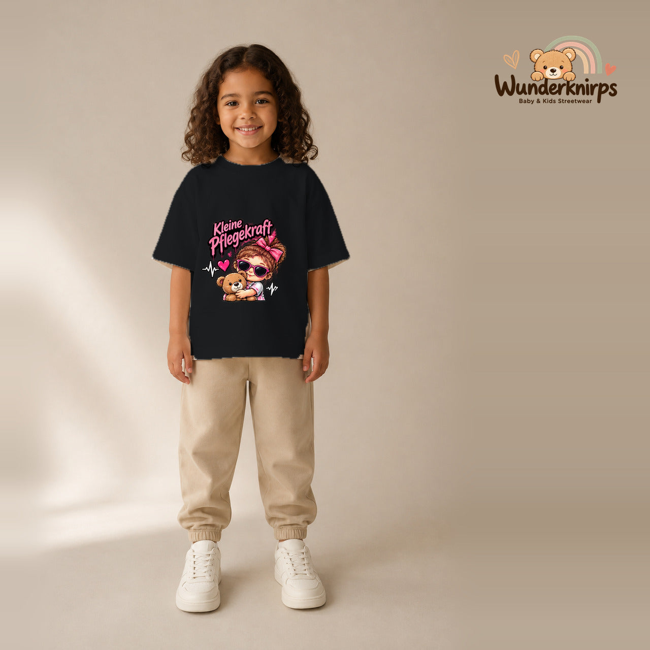 T-Shirt für Mädchen in Schwarz mit Motiv „Kleine Pflegekraft“, getragen von einem Kind – Wunderknirps.