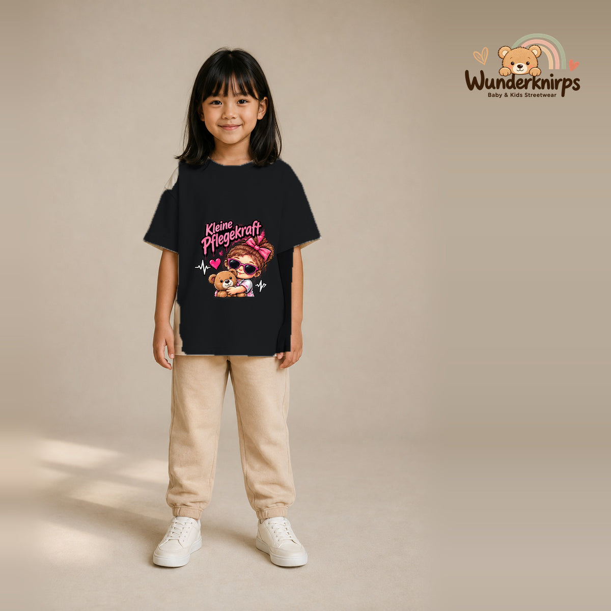 T-Shirt für Mädchen in Schwarz mit Motiv „Kleine Pflegekraft“, getragen von einem Kind – Wunderknirps.