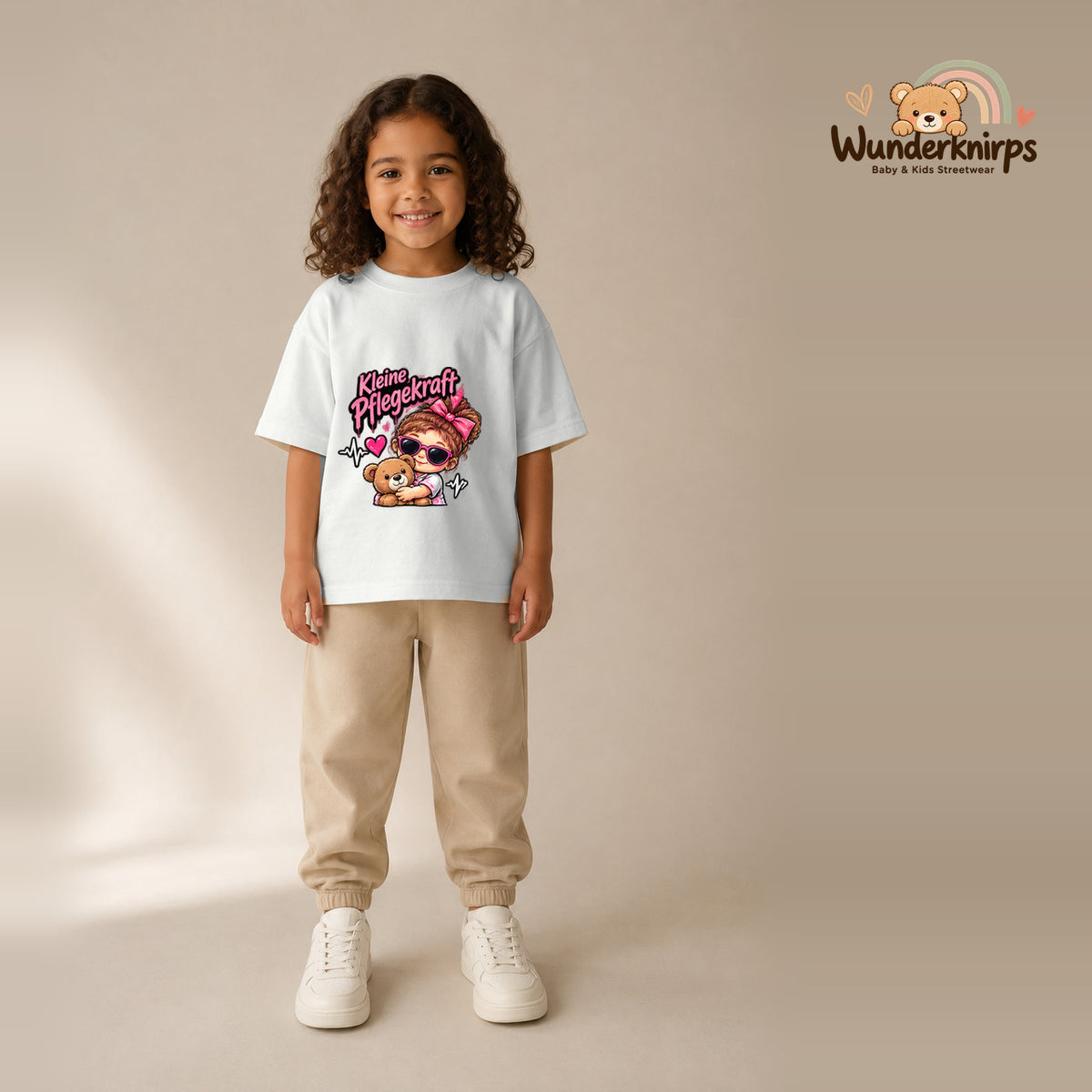 T-Shirt für Mädchen in Weiß mit Motiv „Kleine Pflegekraft“, getragen von einem Kind – Wunderknirps.