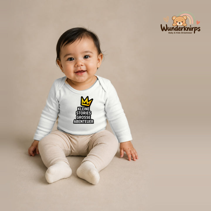 Babybody für Mädchen in Weiß mit Motiv „Kleine Stories große Abenteuer“, getragen von einem Kind – Wunderknirps.