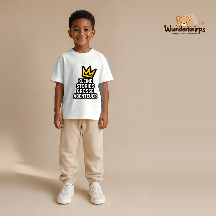 T-Shirt für Jungen in Weiß mit Motiv „Kleine Stories große Abenteuer“, getragen von einem Kind – Wunderknirps.