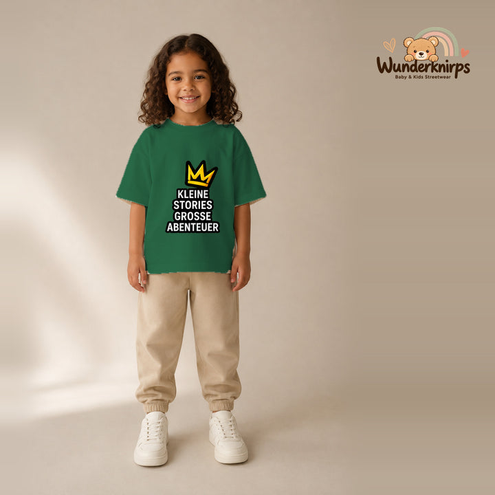 T-Shirt für Mädchen in Grün mit Motiv „Kleine Stories große Abenteuer“, getragen von einem Kind – Wunderknirps.