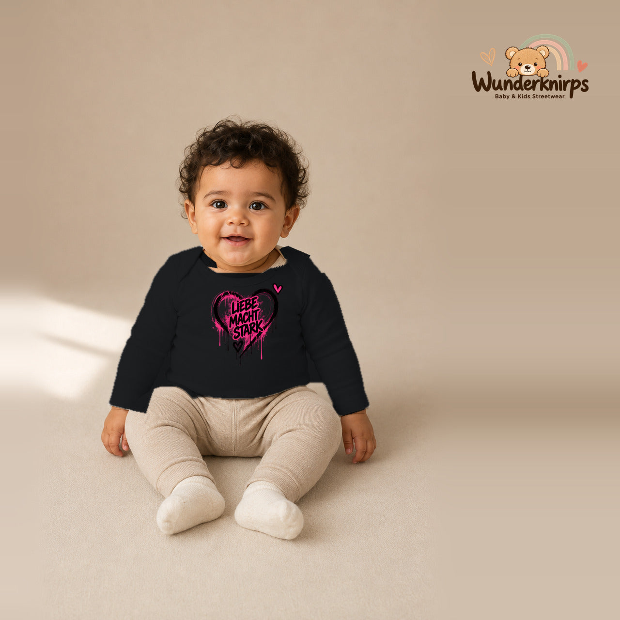 Babybody für Jungen in Schwarz mit Motiv „Liebe macht stark“, getragen von einem Kind – Wunderknirps.