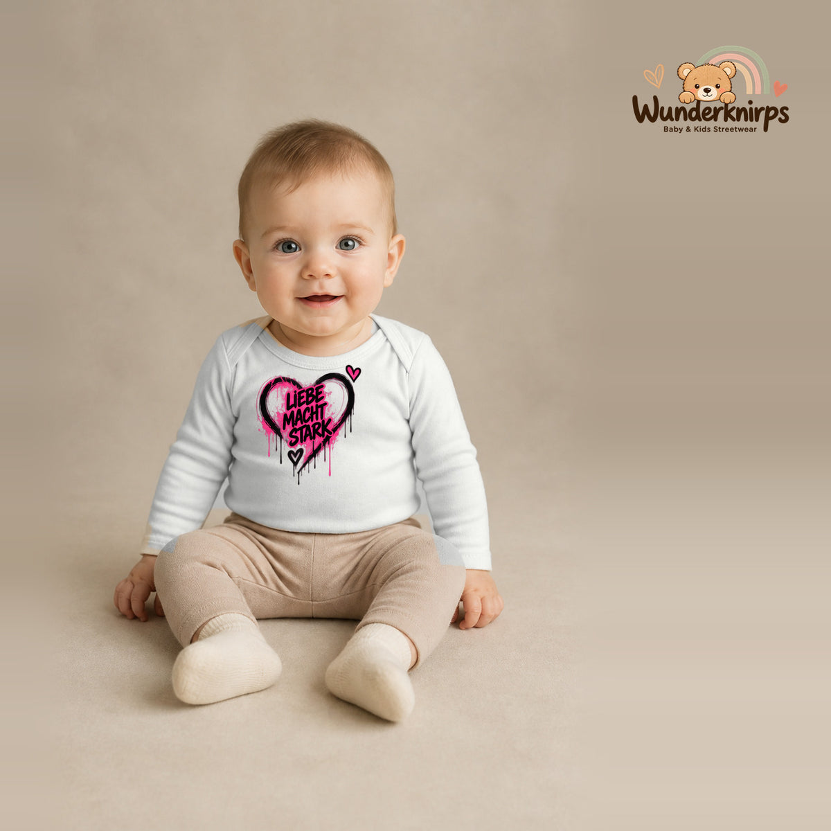 Babybody für Jungen in Weiß mit Motiv „Liebe macht stark“, getragen von einem Kind – Wunderknirps.