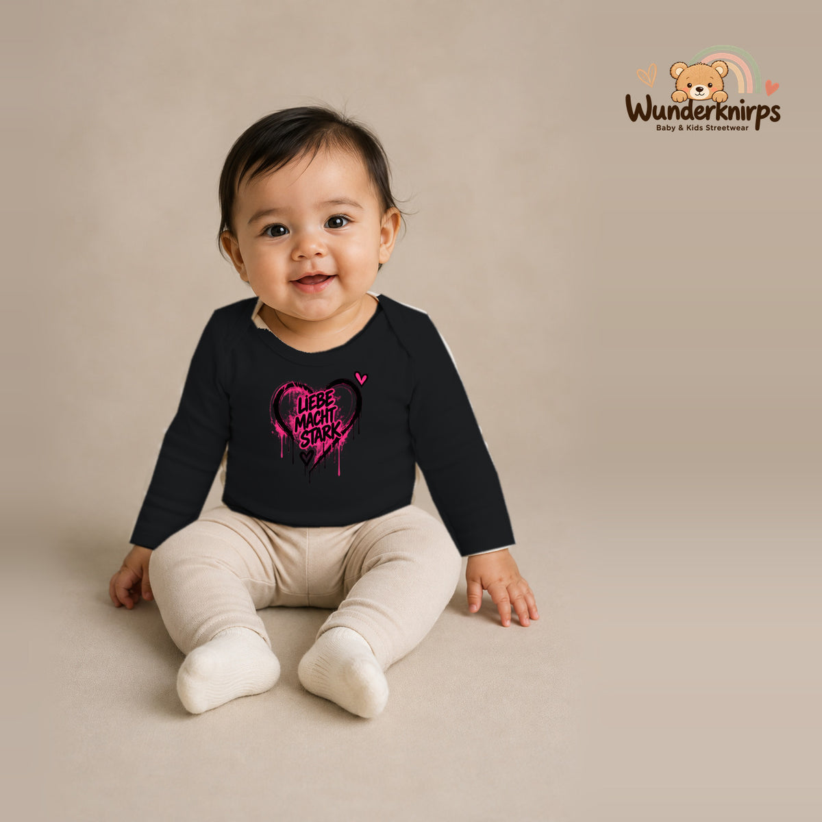 Babybody für Mädchen in Schwarz mit Motiv „Liebe macht stark“, getragen von einem Kind – Wunderknirps.