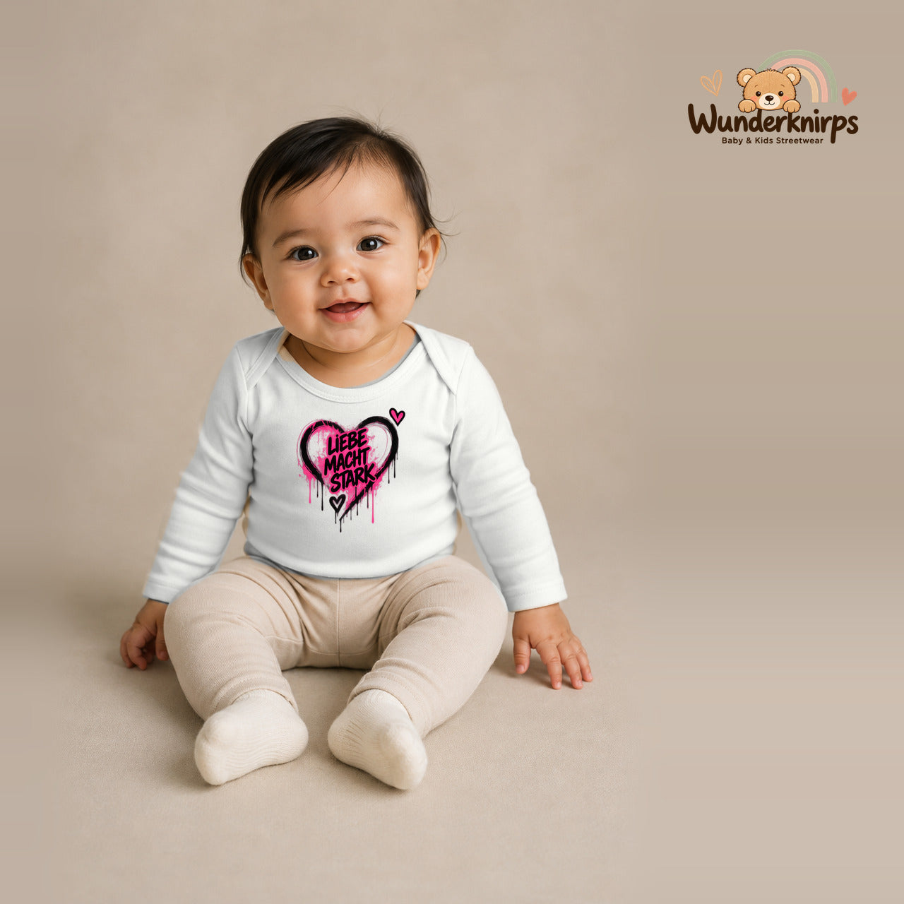 Babybody für Mädchen in Weiß mit Motiv „Liebe macht stark“, getragen von einem Kind – Wunderknirps.