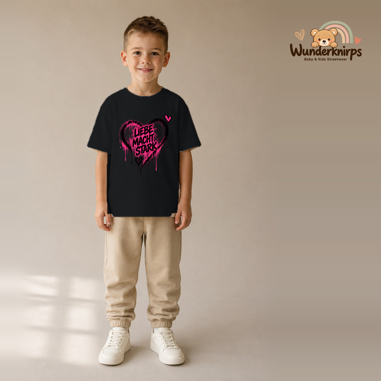 T-Shirt für Jungen in Schwarz mit Motiv „Liebe macht stark“, getragen von einem Kind – Wunderknirps.
