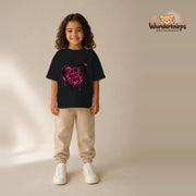 T-Shirt für Mädchen in Schwarz mit Motiv „Liebe macht stark“, getragen von einem Kind – Wunderknirps.