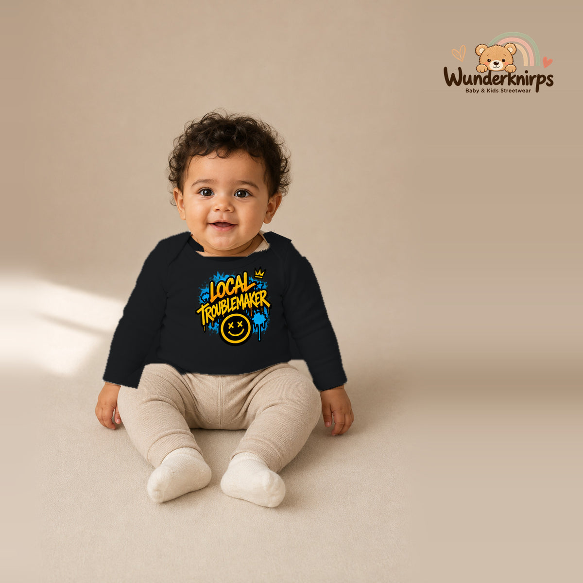 Babybody für Jungen in Schwarz mit Motiv „Local Troublemaker“, getragen von einem Kind – Wunderknirps.
