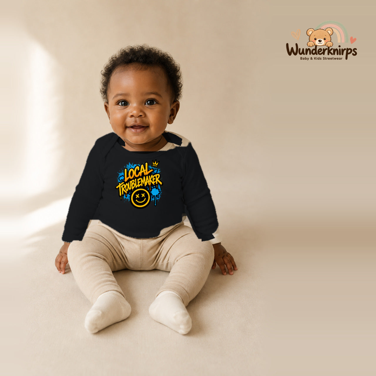 Babybody für Mädchen in Schwarz mit Motiv „Local Troublemaker“, getragen von einem Kind – Wunderknirps.