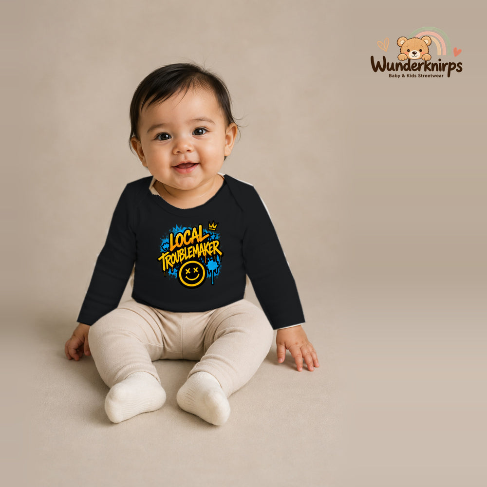 Babybody für Mädchen in Schwarz mit Motiv „Local Troublemaker“, getragen von einem Kind – Wunderknirps.