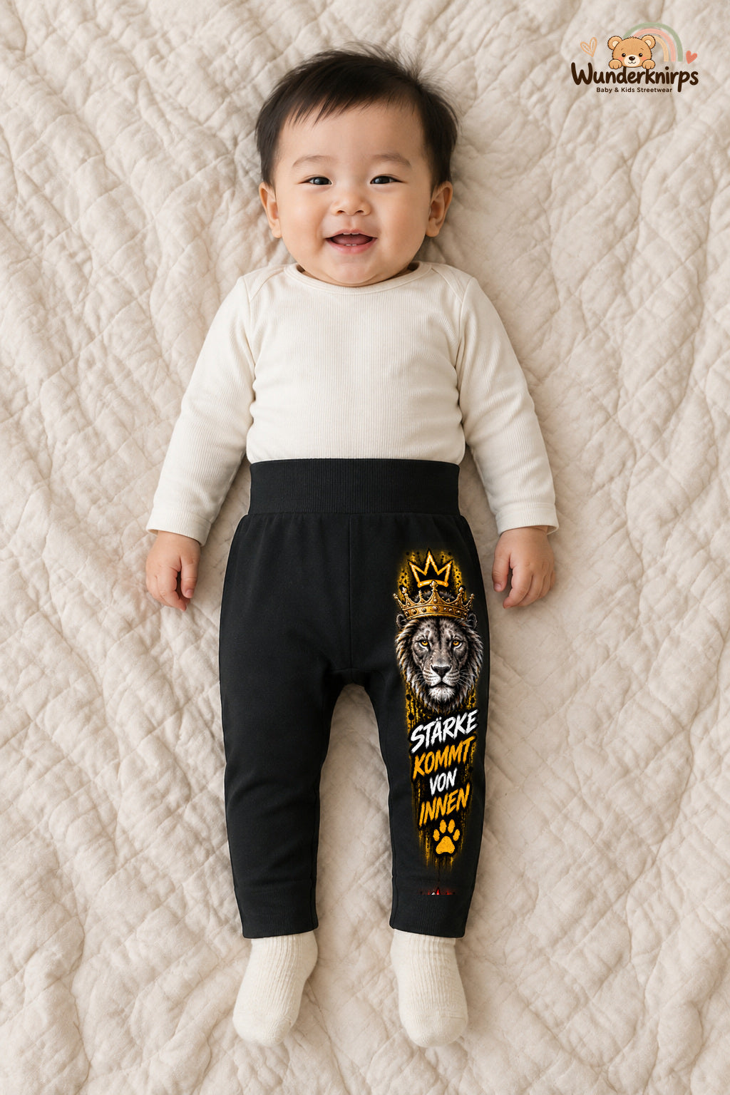 Löwe Alltagsheld – Stärke kommt von innen – Babyhose für Jungen: Schwarz mit Löwe-Druck am Hosenbein – Wunderknirps.
