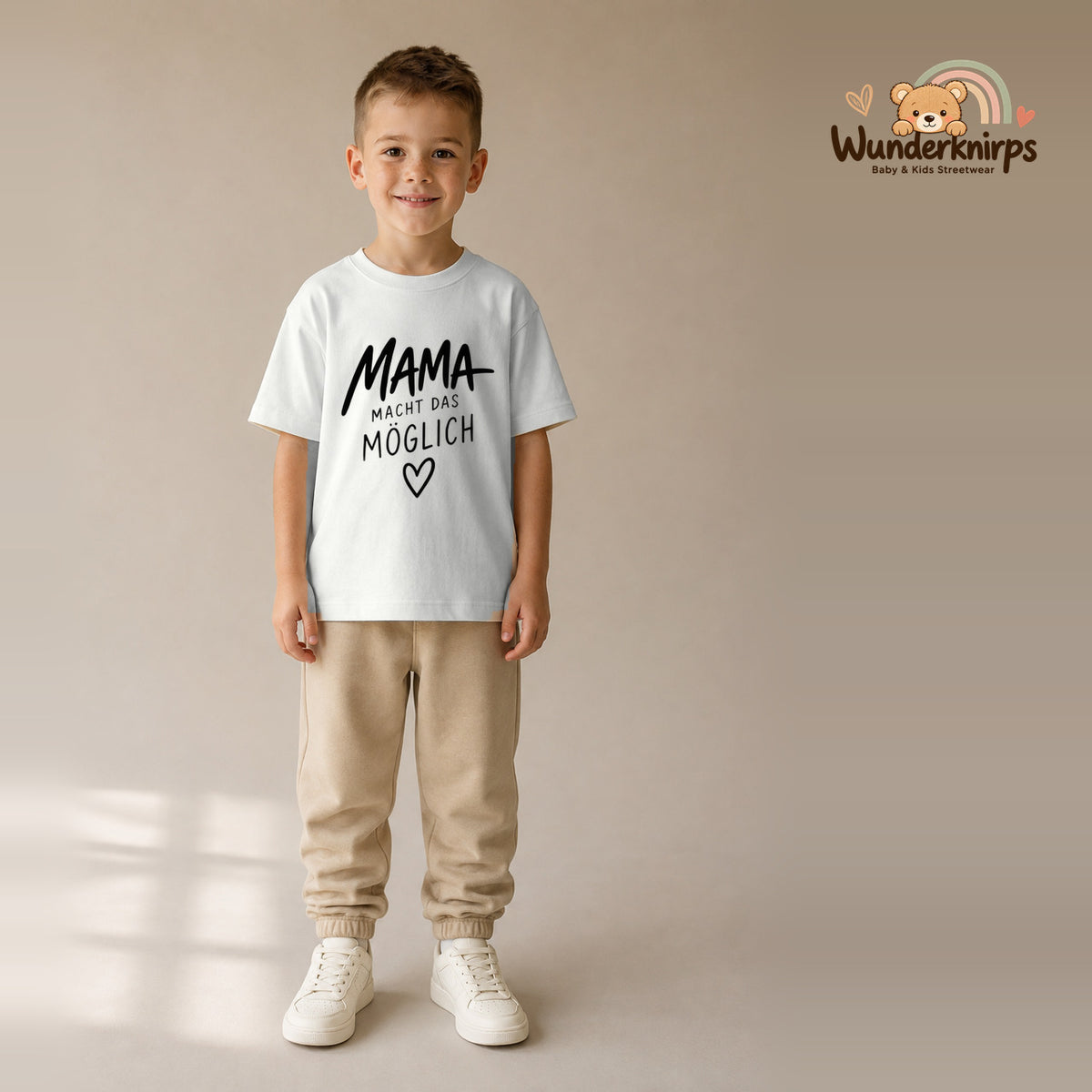 T-Shirt für Jungen in Weiß mit Motiv „Mama macht das möglich“, getragen von einem Kind – Wunderknirps.