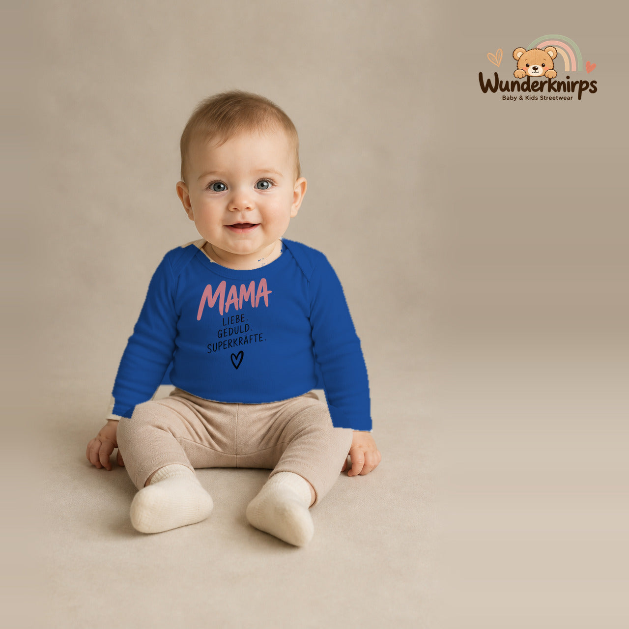 Babybody für Jungen in Blau mit Motiv „Mama Superkräfte“, getragen von einem Kind – Wunderknirps.