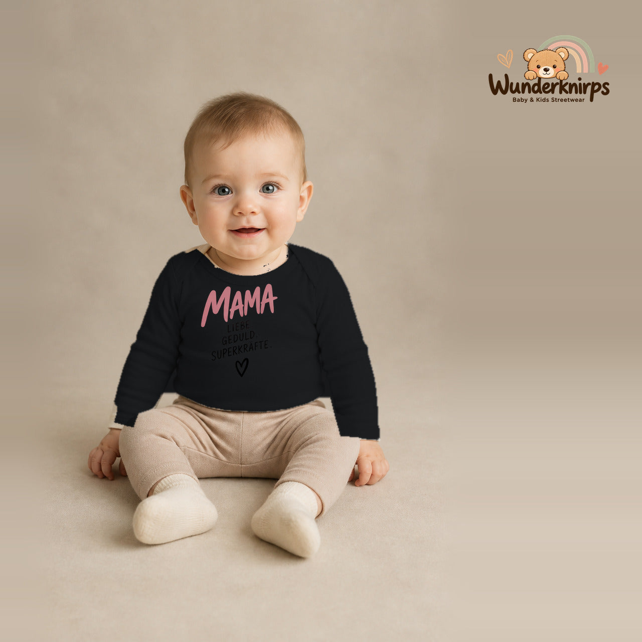 Babybody für Jungen in Schwarz mit Motiv „Mama Superkräfte“, getragen von einem Kind – Wunderknirps.