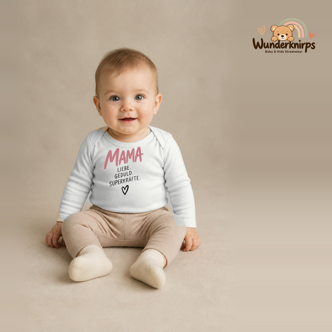 Babybody für Jungen in Weiß mit Motiv „Mama Superkräfte“, getragen von einem Kind – Wunderknirps.