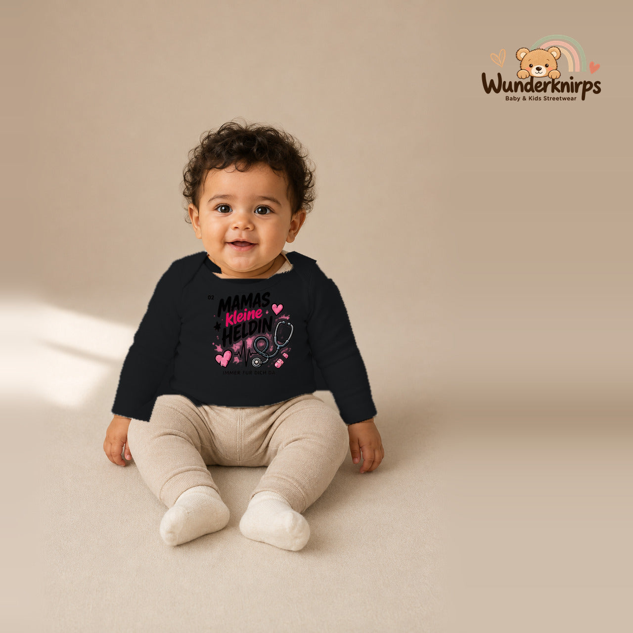 Babybody für Jungen in Schwarz mit Motiv „Mamas kleine Heldin“, getragen von einem Kind – Wunderknirps.