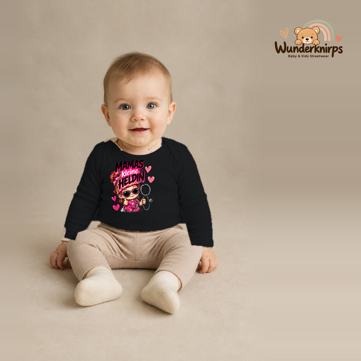 Babybody für Jungen in Schwarz mit Motiv „Mamas kleine Heldin“, getragen von einem Kind – Wunderknirps.