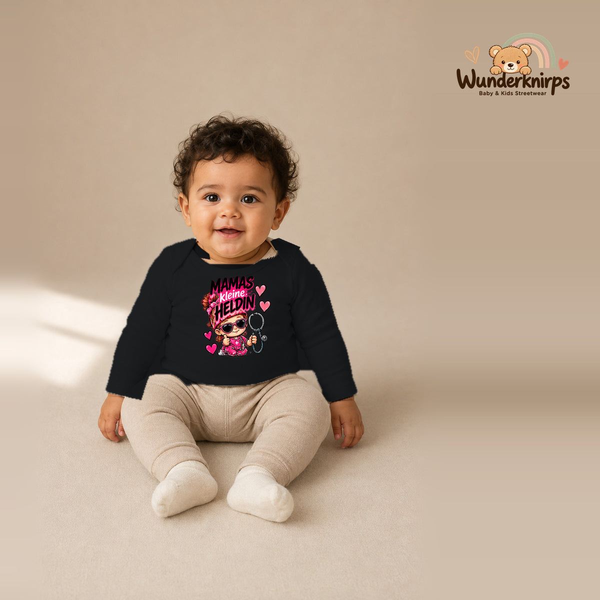 Babybody für Jungen in Schwarz mit Motiv „Mamas kleine Heldin“, getragen von einem Kind – Wunderknirps.