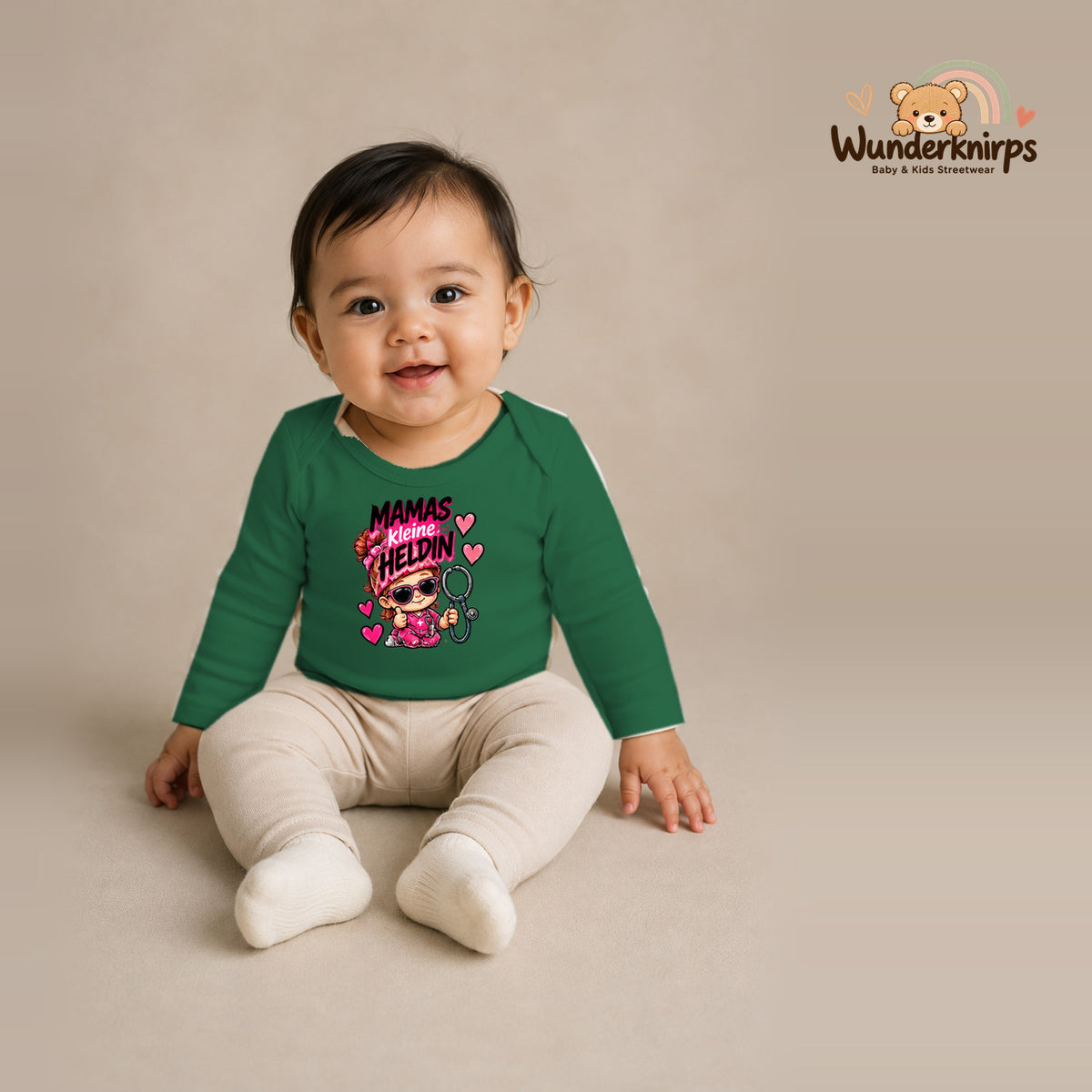 Babybody für Mädchen in Grün mit Motiv „Mamas kleine Heldin“, getragen von einem Kind – Wunderknirps.