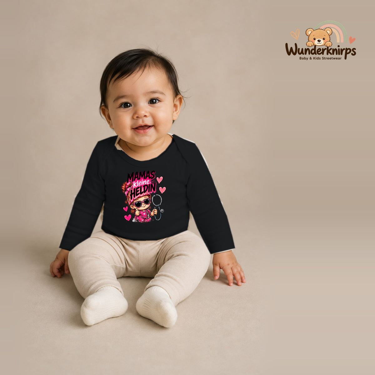 Babybody für Mädchen in Schwarz mit Motiv „Mamas kleine Heldin“, getragen von einem Kind – Wunderknirps.