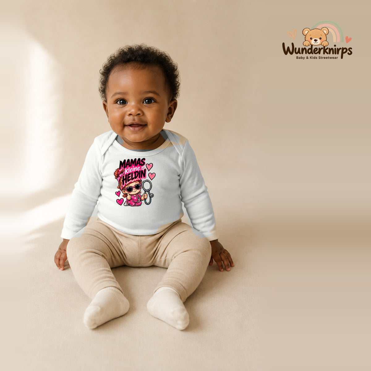 Babybody für Mädchen in Weiß mit Motiv „Mamas kleine Heldin“, getragen von einem Kind – Wunderknirps.