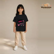 T-Shirt für Mädchen in Schwarz mit Motiv „Mamas kleine Heldin“, getragen von einem Kind – Wunderknirps.