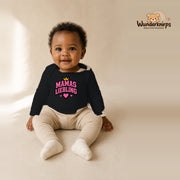 Babybody für Mädchen in Schwarz mit Motiv „Mamas Liebling“, getragen von einem Kind – Wunderknirps.