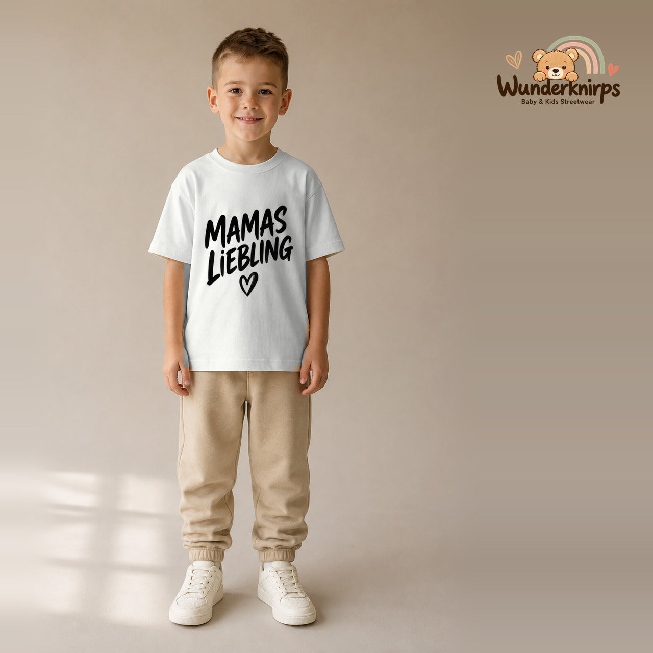 T-Shirt für Jungen in Weiß mit Motiv „Mamas Liebling“, getragen von einem Kind – Wunderknirps.