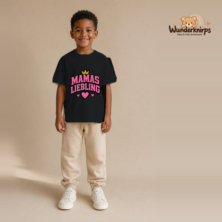 T-Shirt für Jungen in Schwarz mit Motiv „Mamas Liebling“, getragen von einem Kind – Wunderknirps.