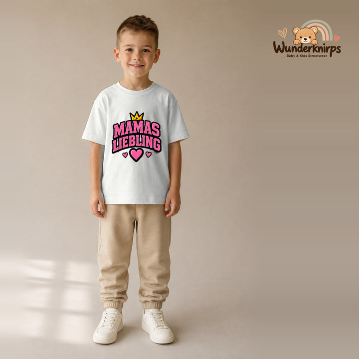 T-Shirt für Jungen in Weiß mit Motiv „Mamas Liebling“, getragen von einem Kind – Wunderknirps.
