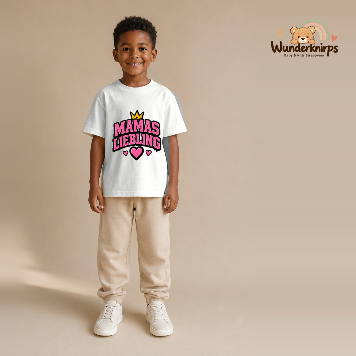 T-Shirt für Jungen in Weiß mit Motiv „Mamas Liebling“, getragen von einem Kind – Wunderknirps.