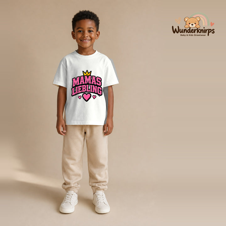 T-Shirt für Jungen in Weiß mit Motiv „Mamas Liebling“, getragen von einem Kind – Wunderknirps.