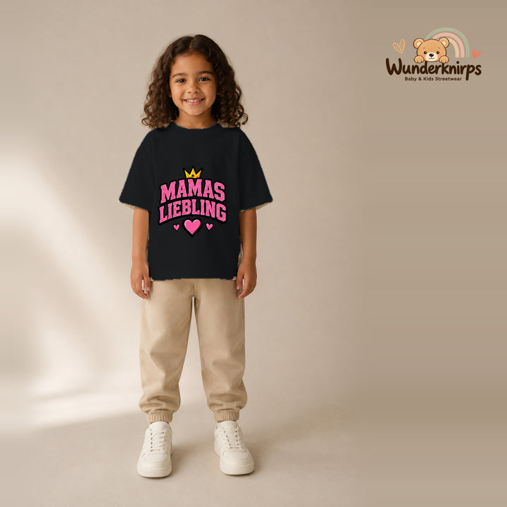T-Shirt für Mädchen in Schwarz mit Motiv „Mamas Liebling“, getragen von einem Kind – Wunderknirps.
