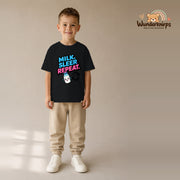 T-Shirt für Jungen in Schwarz mit Motiv „Milk Sleep Repeat“, getragen von einem Kind – Wunderknirps.