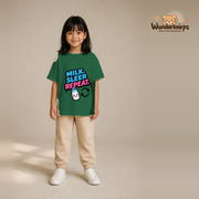 T-Shirt für Mädchen in Grün mit Motiv „Milk Sleep Repeat“, getragen von einem Kind – Wunderknirps.