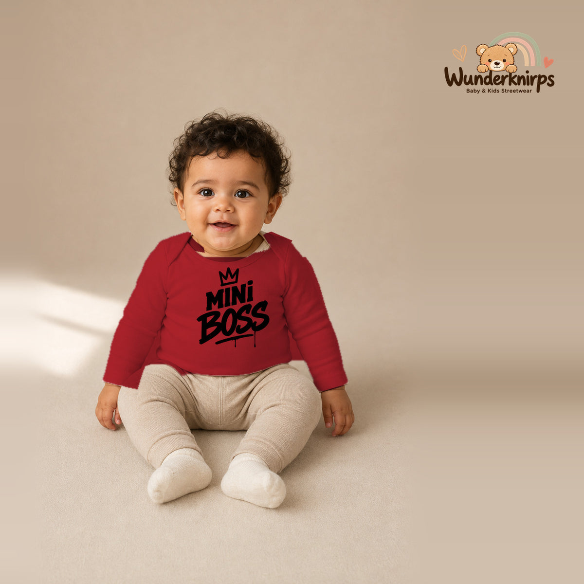 Babybody für Jungen in Rot mit Motiv „Mini Boss“, getragen von einem Kind – Wunderknirps.