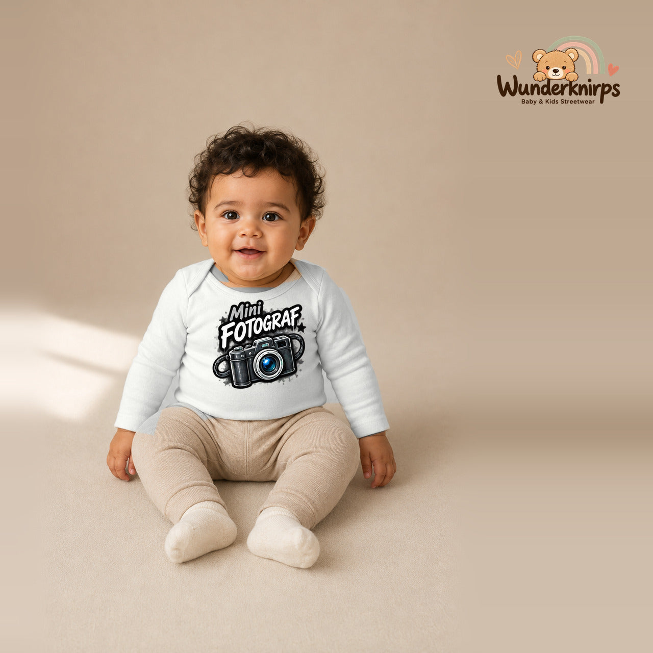 Babybody für Jungen in Weiß mit Motiv „Mini Fotograf“, getragen von einem Kind – Wunderknirps.