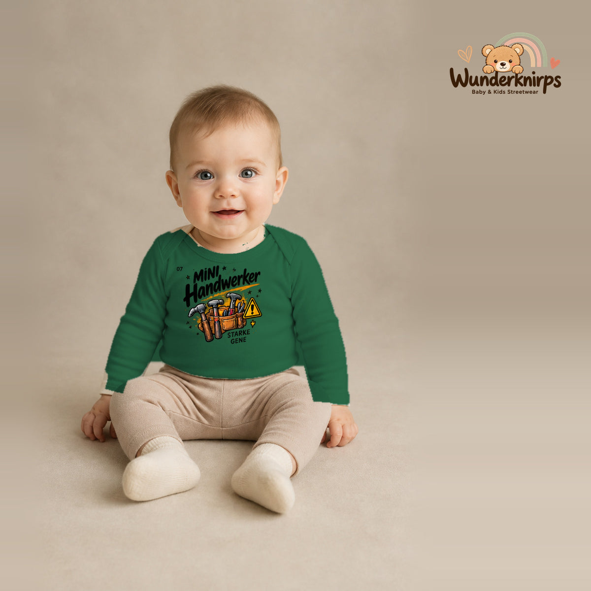 Babybody für Jungen in Grün mit Motiv „Mini Handwerker“, getragen von einem Kind – Wunderknirps.